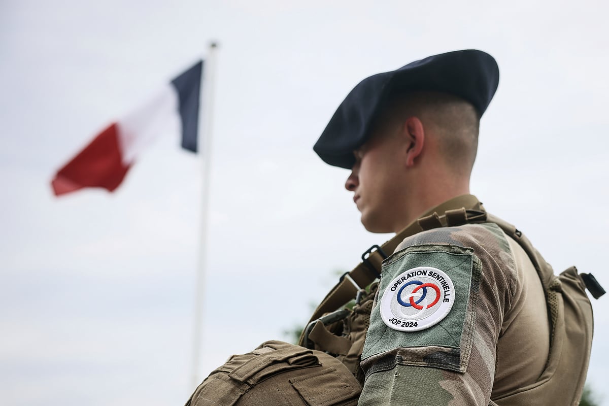 A soldier stands by the French flag at the military camp set up in the Vincennes woods, Monday, July 15, 2024 just outside Paris - AP